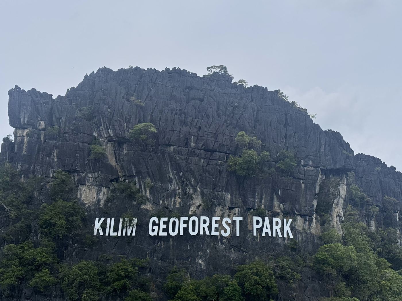 Kilim Geoforest Park sign on the limestone cliff